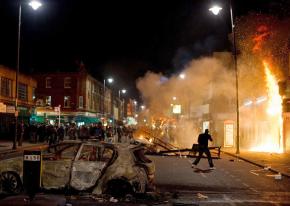 Police watch as rioters set a building on fire