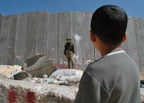 A Palestinian child looks on at Israel's apartheid wall in the West Bank